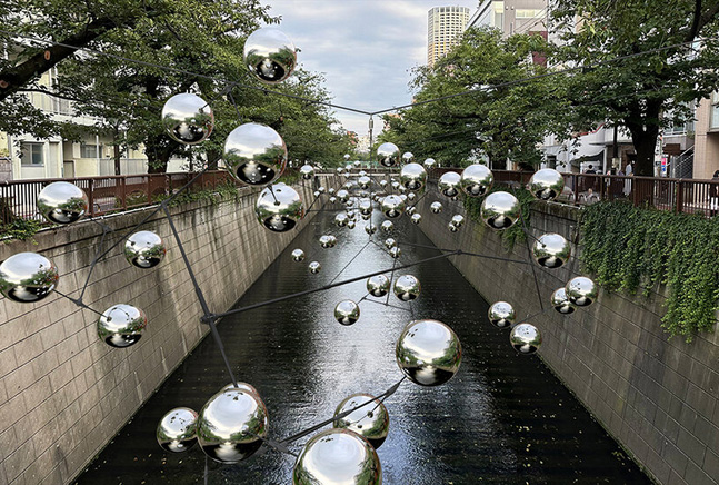 Reflective spheres by vincent leroy form swirling constellation above canal in tokyo